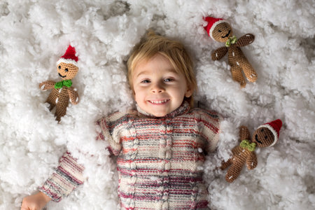Cute toddler child, holding knitted toy, playing in the snow with colorful snowmen, smiling happilyの写真素材
