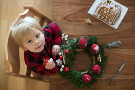 Little cute blonde toddler boy, making advent wreath at home, decorating itの写真素材