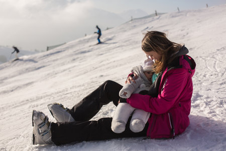 Young mother, breastfeeding her baby boy on top of mountain on sunset in Austrian Alps, beautiful scenery landscapeの写真素材