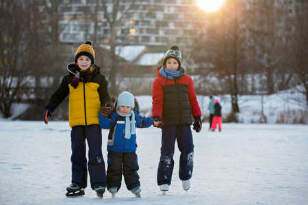 Happy children, skating on a frozen lake in the park, wintertime