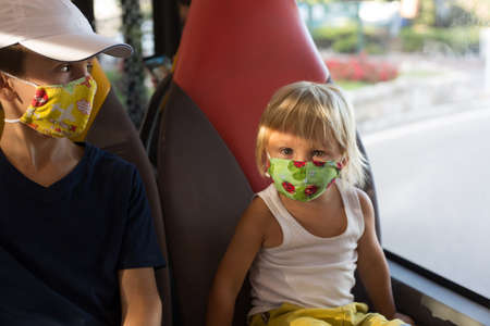 Children, boy brothers, wearing masks in a bus, public transportation requirement