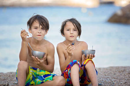 Cute boy, child, eating spaghetti on the beach, enjoying dinner outdoorsの写真素材