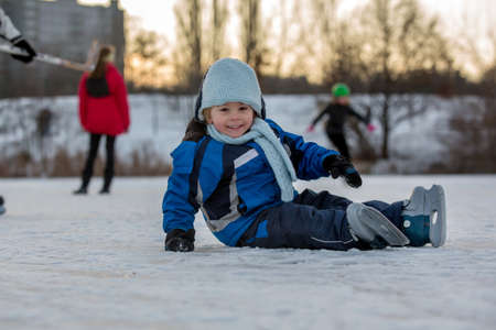 Happy children, skating on a frozen lake in the park, wintertime