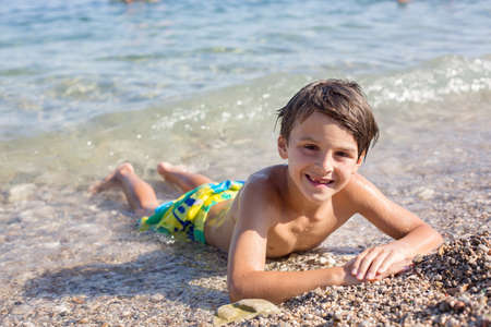 Sweet child, preteen boy, lying on the beach in France on sunset, summertimeの写真素材
