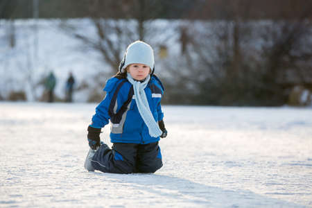 Happy children, skating on a frozen lake in the park, wintertime