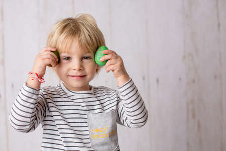 Sweet toddler child, cute boy playing with colorful easter eggs, studio shot