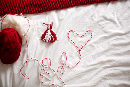 Cute child, blond boy, playing with white and red bracelet, called Martenitsa