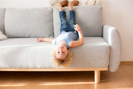 Toddler child, hanging upside down from a couch at home, smiling happily