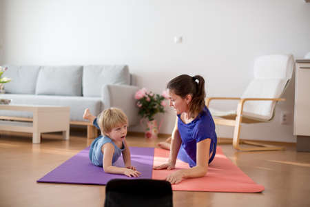 Mother and children, exercising at home during coronavirus, people making gymnastic at home, while...