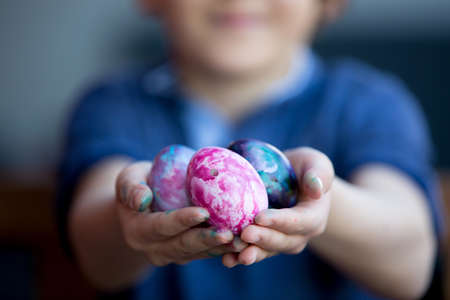 Sweet children, brothers, coloring and paiting eggs for Easter in garden, outdoors at home in...
