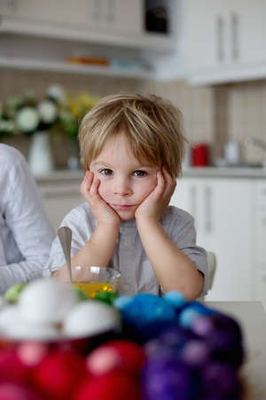 Children, boy siblings, coloring eggs for Easter at home