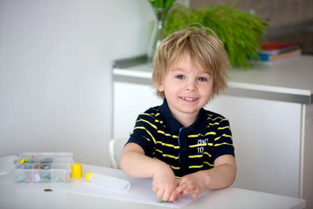 Blond toddler child, creating picture with application cut paper animals, gift for mom form Mothers...