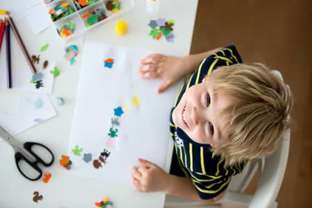 Blond toddler child, creating picture with application cut paper animals, gift for mom form Mothers dayの写真素材