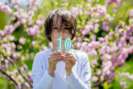 Child, holding number candles with 10 on them, for his birthdayの写真素材