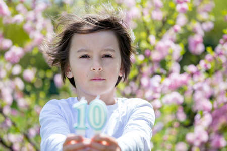 Child, holding number candles with 10 on them, for his birthday
