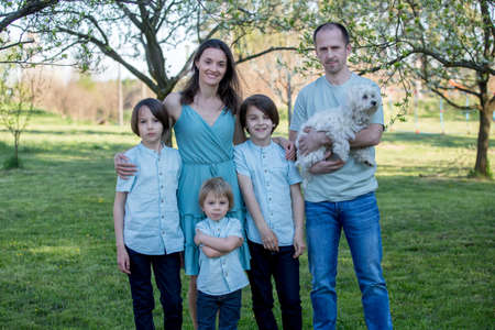 Beautiful family with kids, mom, dad, three boys and a dog, playing in the park together