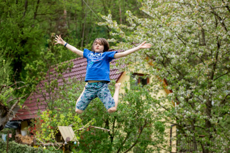 Child, jumping high on a trampoline in backyard