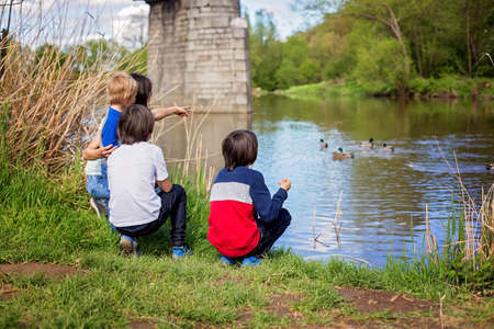 Family with children, feeding ducks in a river in front of old wooden cottage on brick pillar in The Radbuza River, near Chotesov, Czech Republic, Europeの写真素材
