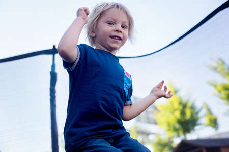 Cute little boy with static electricy hair, having his funny portrait taken outdoors on a trampolineの写真素材