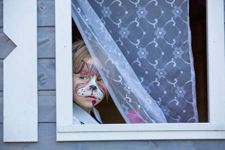Little toddler baby boy, child with painted face as a dog, playing with pet dog in the garden on birthday partyの写真素材