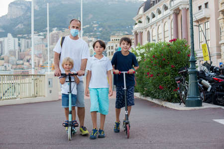 Family with scooters in Monaco on a summer holiday, enjoying view of Monaco city