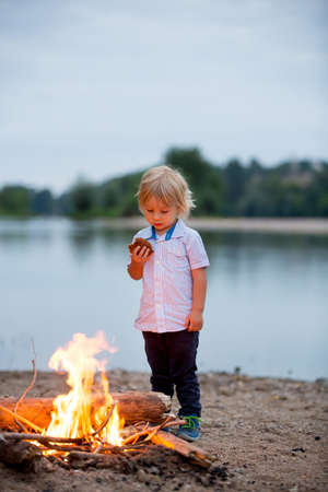 Family having picnic and campfire in the evening near river summertime