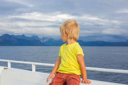 Child, cute boy, looking at the mountains from a ferry in Nortern Norway on his way to Lofotenの写真素材