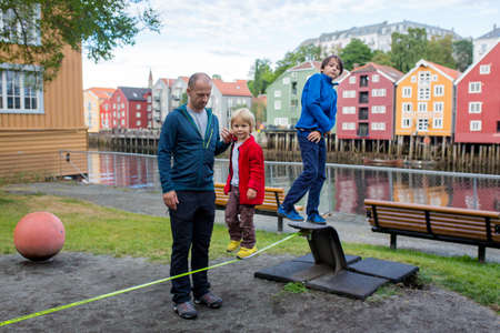 Happy family, visiting Trondheim, Norway during the summer, enjoying the city, kids walking on a ropeの写真素材