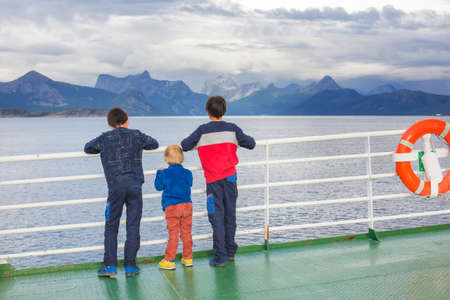 Children, cute boys, looking at the mountains from a ferry in Nortern Norway on his way to Lofotenの写真素材