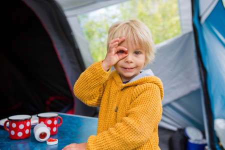 Cute little toddler boy, eating vitamins on a family holiday to improove his health and for better imunity while traveling and sleeping in a tent, Norway wild campingの写真素材
