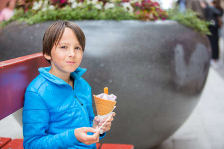 Cute blond child with black shirt, eating churros on the street in the city of Stockhlom, sweet...