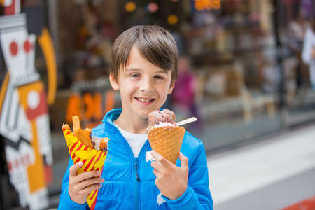 Cute blond child with black shirt, eating churros on the street in the city of Stockhlom, sweet...