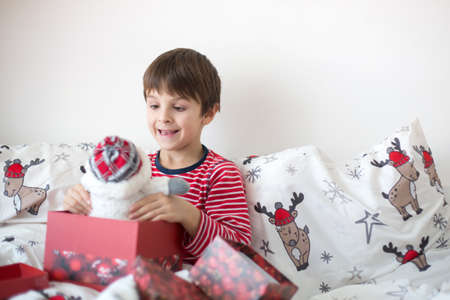 Happy children, opening christmas presents in bed on christmas morningの写真素材