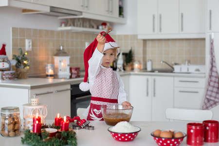 Cute blond child, boy and his mom, baking christmas cookies at home, having funの写真素材