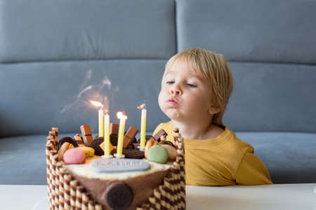 Cute child, boy, celebrating his birthday at home with colorful cake with siblingsの写真素材