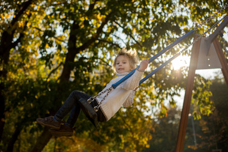 Happy children, playing with pet dog in autumn park on a sunny day, foliage and leaves all around themの写真素材