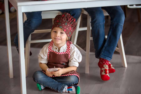 Cute blond child, toddler boy, baking christmas cookies at home, having funの写真素材