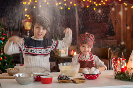 Cute blond child and his brothers,  baking christmas cookies at home, having funの写真素材