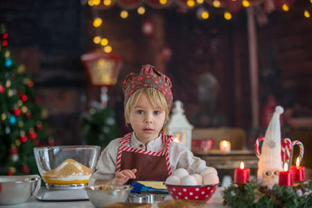 Cute blond child, toddler boy, baking christmas cookies at home, having funの写真素材
