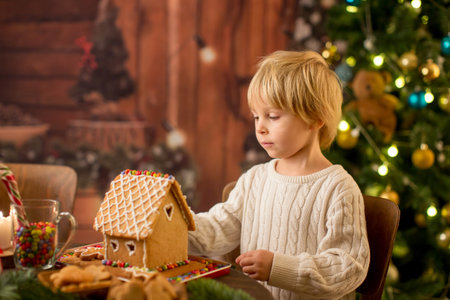 Blond toddler child, cute boy, making Christmas ginger bread house at homeの写真素材