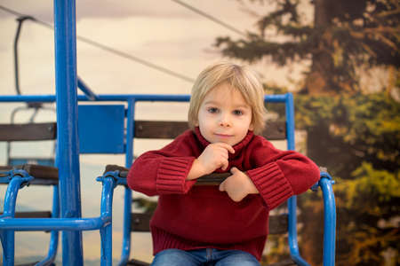 Cute toddler child, blond boy, sitting in old vintage ski lift, summertimeの写真素材
