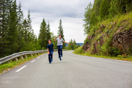 Children, running on an empty road in Norway, beautiful nature around