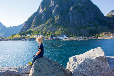 Happy family, enjoying the pier in Sorvagen, Lofoten island, Norway. Children, running on a sunny day on the rocks, enjoying good weatherの写真素材
