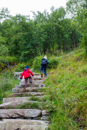 Children, toddler, brothers  climbing the stairs to Reinebringen, trekking path leading to the top...