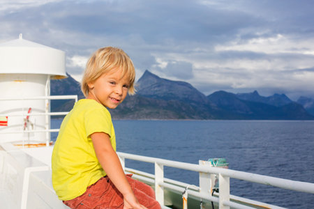 Child, cute boy, looking at the mountains from a ferry in Nortern Norway on his wayの写真素材
