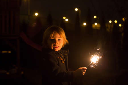 Cute child, holding sparkler at new year eve in garden, happy kidの写真素材