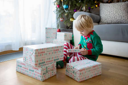 Happy child, toddler boy, opening presents on christmas day dressed in pajamasの写真素材