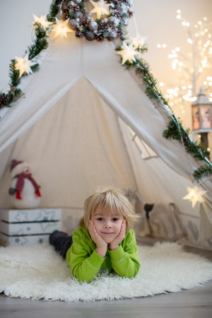 Cute toddler blond child in front of a teepee with pet dog, lying on the floor with sign love, friendsの写真素材