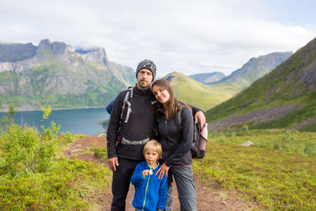 Happy family, standing on a rock and looking over Segla mountain on Senja island, North Norway....