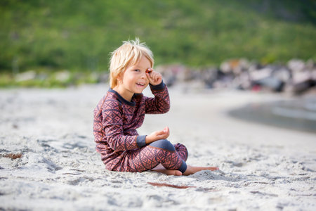 Cute toddler child, eating vitamin pills for children on the beach, child taking additional vitamins for better imunity.Kid eating alfa omega 3 child suplement vitamin pills on a holidayの写真素材